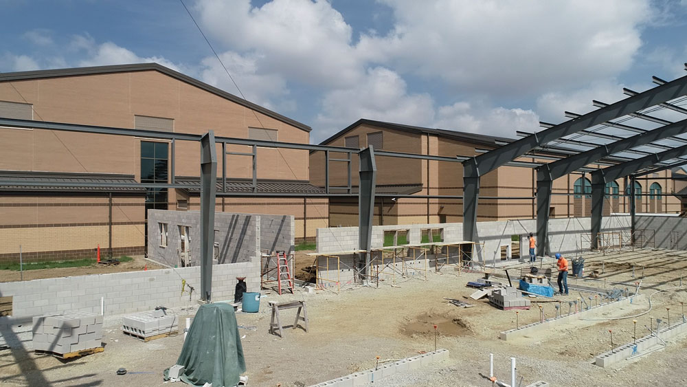 Unfinished school building with steel beams and partial walls.