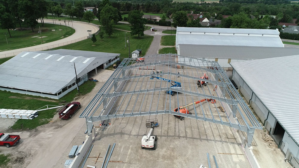 Overhead view of steel rafters in unfinished building with bucket lifts.