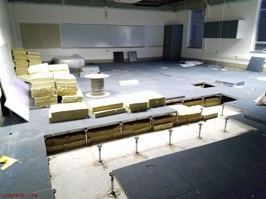 Installing sound insulation under existing raised access flooring in existing computer classroom.
