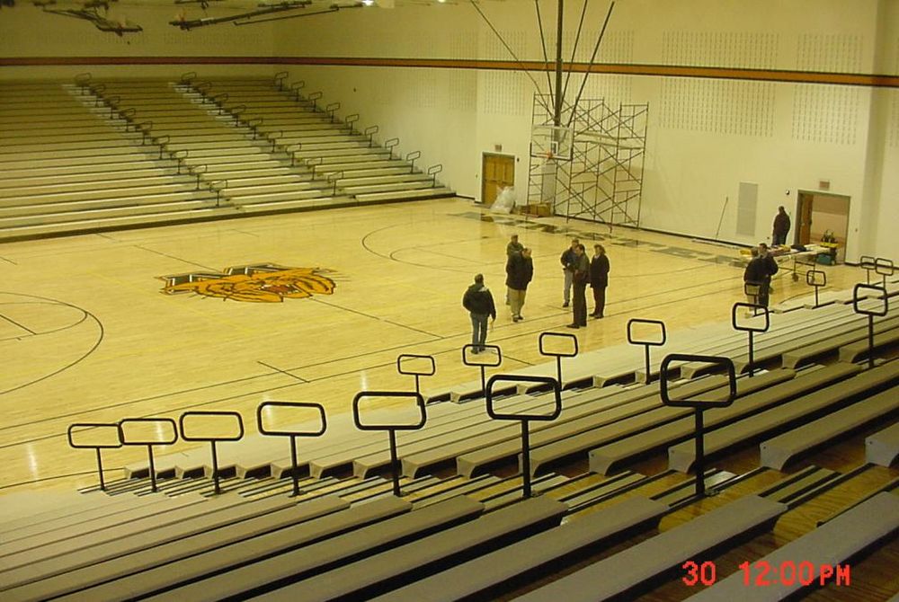 Interior view of 3 court gymnasium with bleachers extended out.