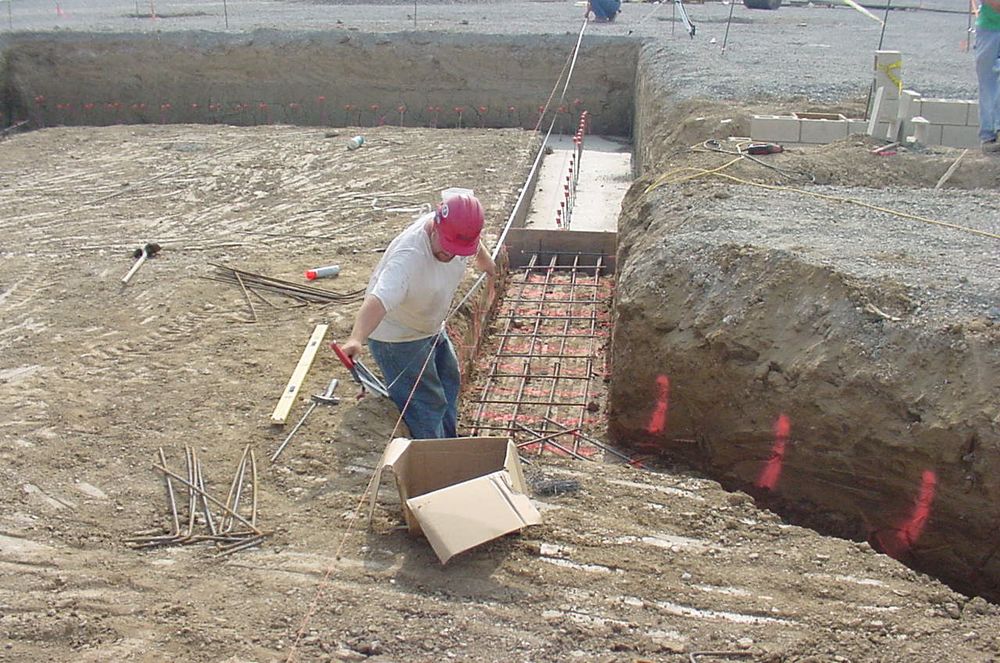 Placing reinforcing steel in excavated footings.