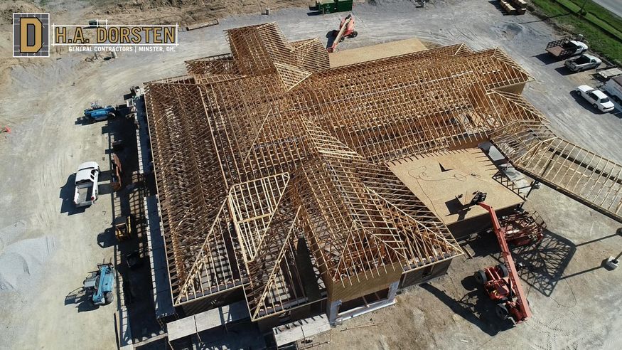 Aerial view of roof sheathing being installed on wood trusses.