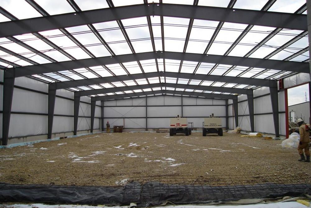 View of the inside of a custom-engineered metal building without roof and concrete floor poured.