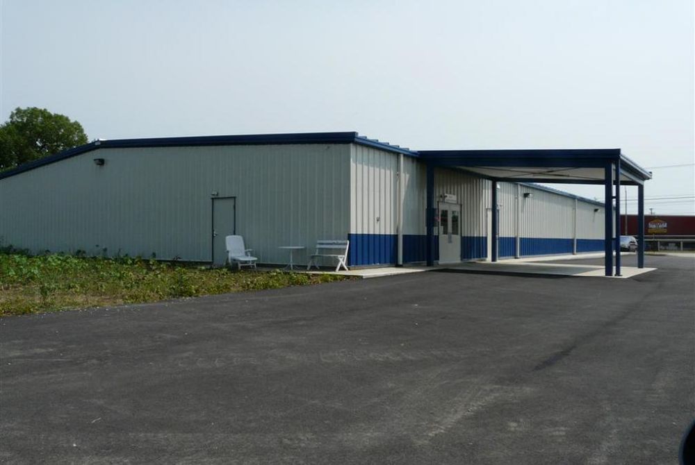 Side and back view of finished custom-engineered metal building with metal wall panels, and large canopy for deliveries.