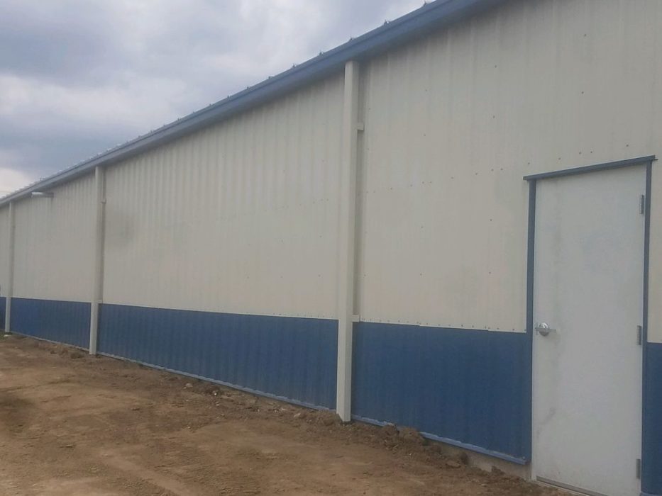 Metal wall panels installed on custom-engineered metal building with walk door.